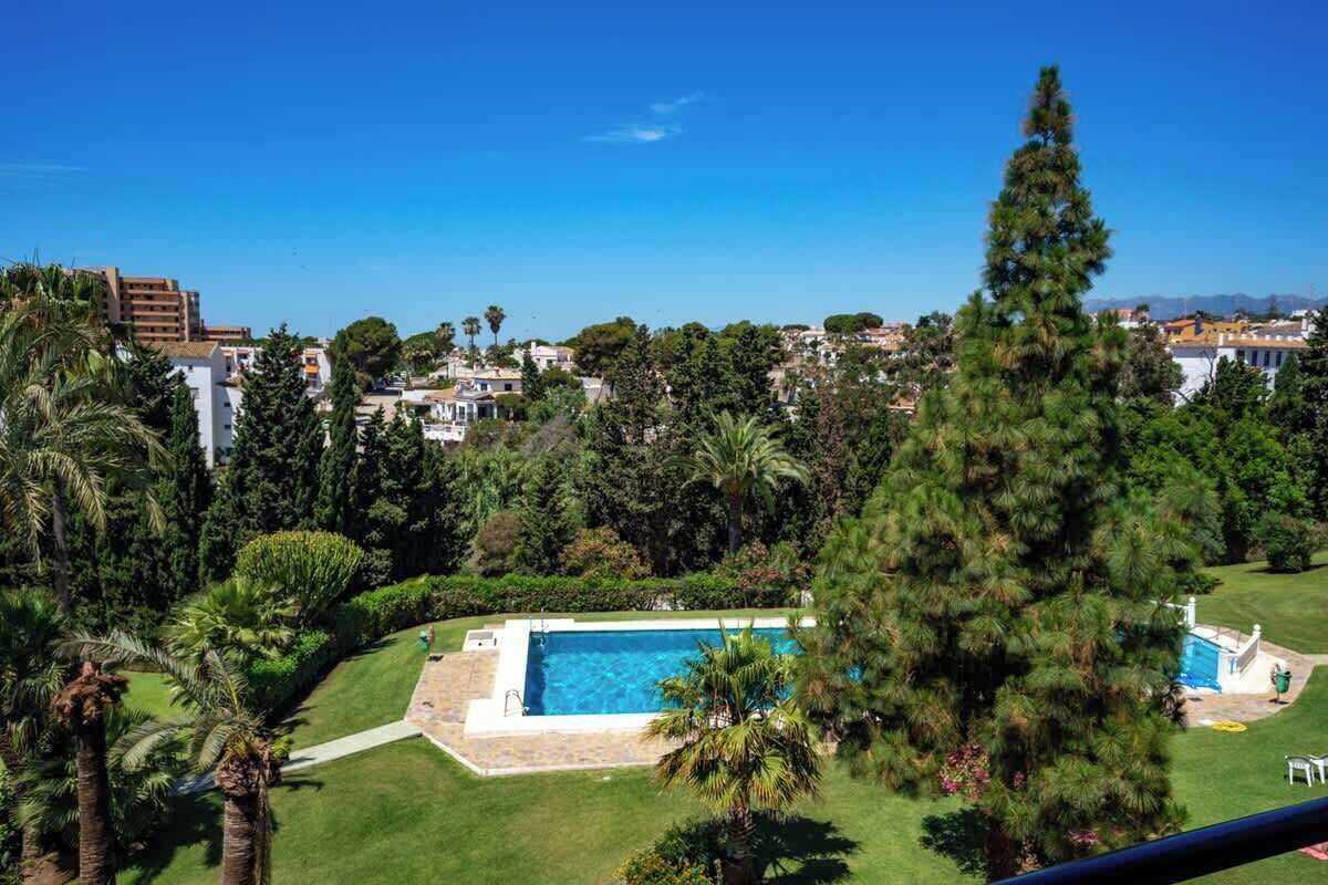 Bairro residencial com piscina, cercado por vegetação exuberante e palmeiras.