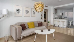 Un salon moderne avec un canapé, une table basse et un luminaire suspendu original.