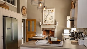 A modern kitchen with a central island, stainless steel appliances, and a brick fireplace.