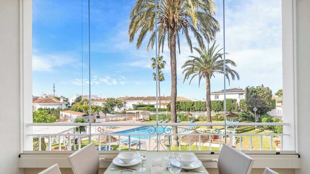 A dining area with a view of a pool and palm trees. - Riviera Bright Balcony by Costarentals - Ref 184 (Las Lagunas de Mijas)
