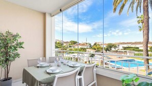 A balcony with a dining table set for two, overlooking a swimming pool and a residential area. - Riviera Bright Balcony by Costarentals - Ref 184 (Las Lagunas de Mijas)