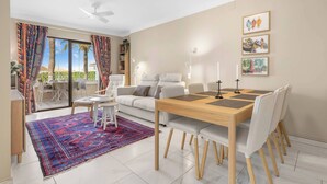 A modern living room with a dining area, large windows, and a view of palm trees. - Riviera Bright Balcony by Costarentals - Ref 184 (Las Lagunas de Mijas)