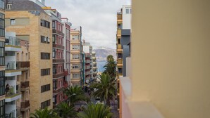 Um edifício residencial com várias andares, varandas, vista para o mar e palmeiras.