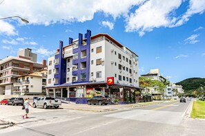 A multi-story building with a restaurant on the ground floor, featuring a blue and white facade and a red awning. - WI-FI 240MB | 350m from Jurerê Beach #JA13 (Florianópolis)