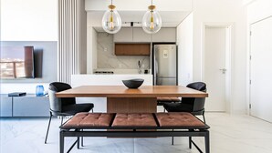 A modern dining area with a wooden table, black chairs, and a bench. There are two pendant lights above the table. - WI-FI 300MB | Rooftop with Pool in Jurerê #JA15 (Florianópolis)