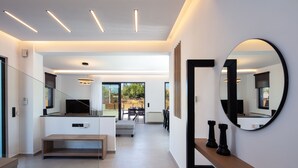 A modern interior with a staircase, a dining area, and a large mirror on the wall.
