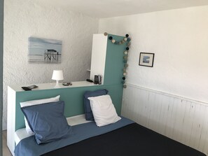 Ein Schlafzimmer mit einem Bett, einem Schreibtisch, einer Lampe, einer Uhr und einem gerahmten Bild an der Wand.
