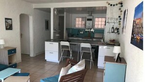 A compact living space with a kitchenette, a dining area with a wooden bench, and a small table. - A 200 M de la Plage (Argelès-sur-Mer)