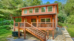 A wooden cabin with a balcony and a staircase leading to the entrance.