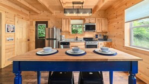 A wooden cabin kitchen with a central island, built-in appliances, and a large window.