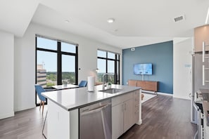 A modern kitchen with a dishwasher, a large island, and a built-in oven. - Placemakr Marymount Ballston (Arlington)