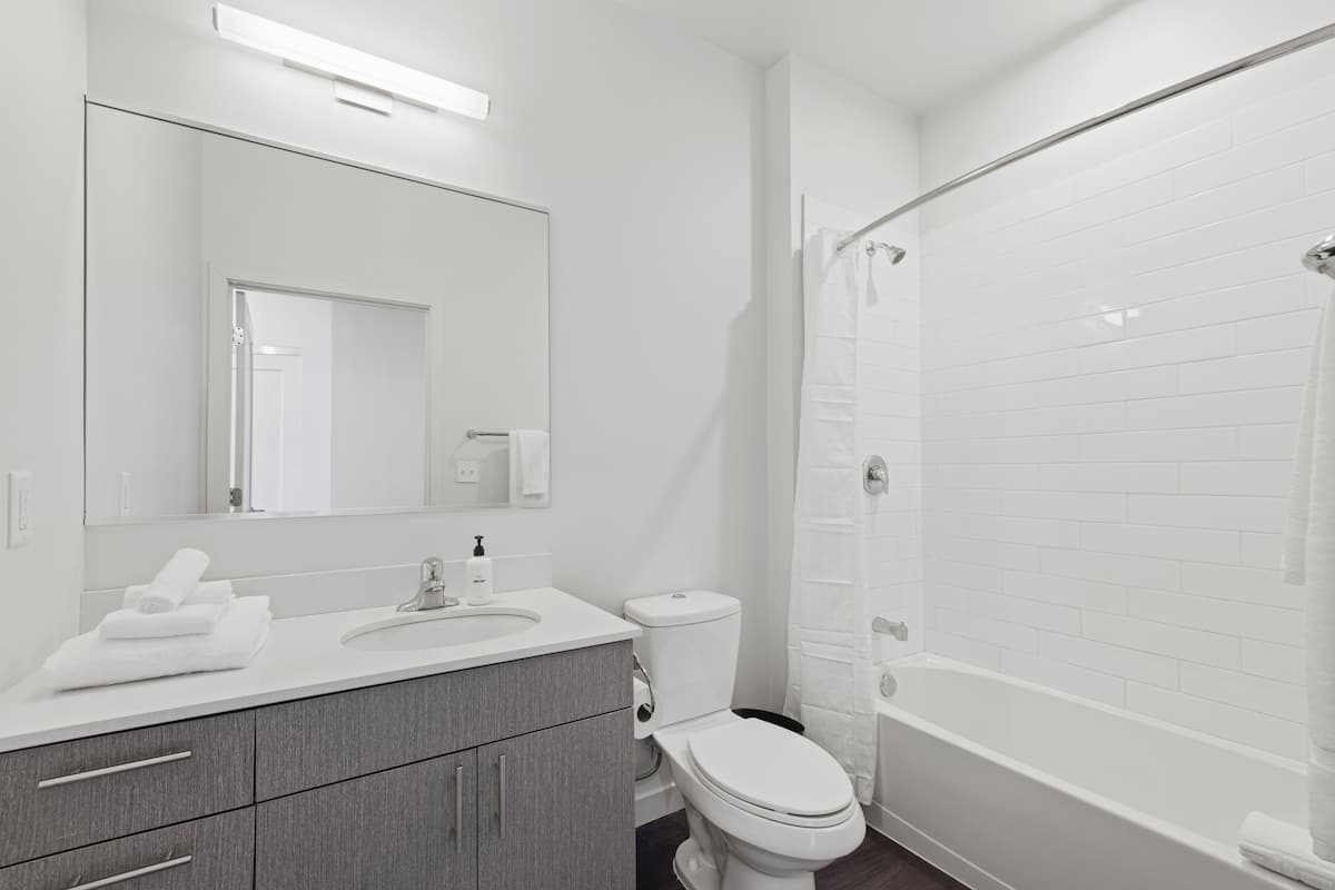 A modern bathroom with a white sink, mirror, and toilet.