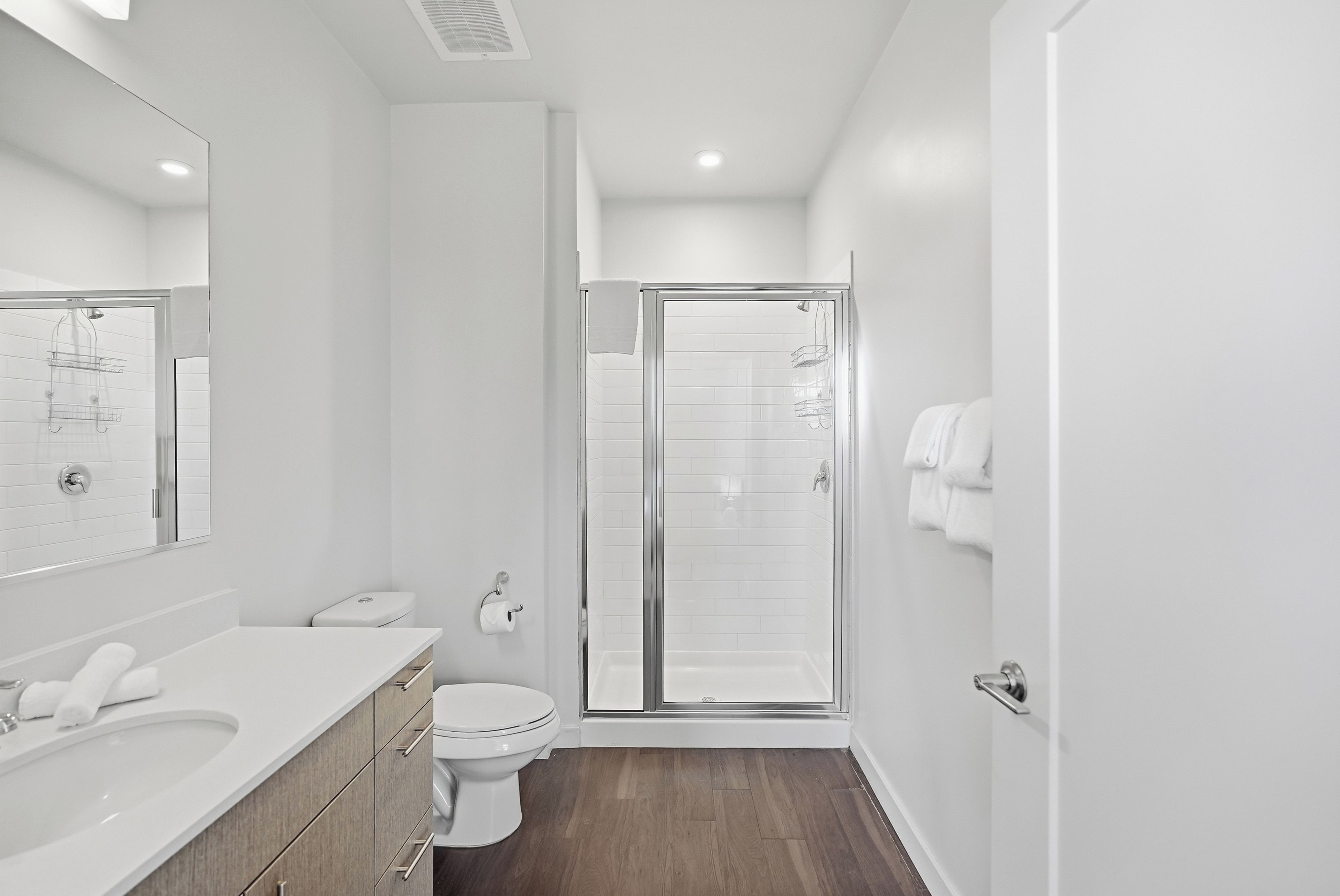 A modern bathroom with a white sink, toilet, and shower area.