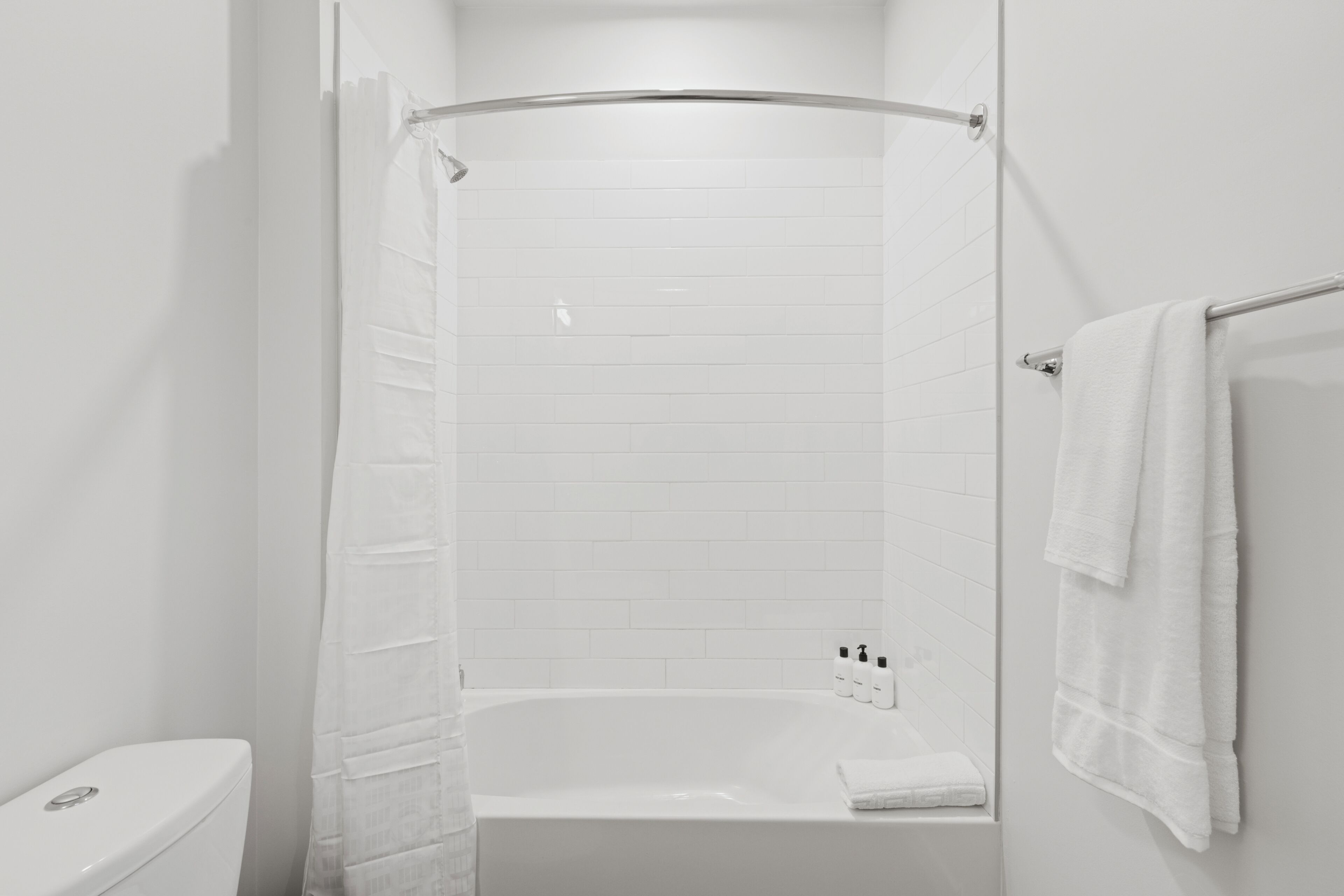 A modern bathroom with a white bathtub, a shower curtain, and a towel rack.