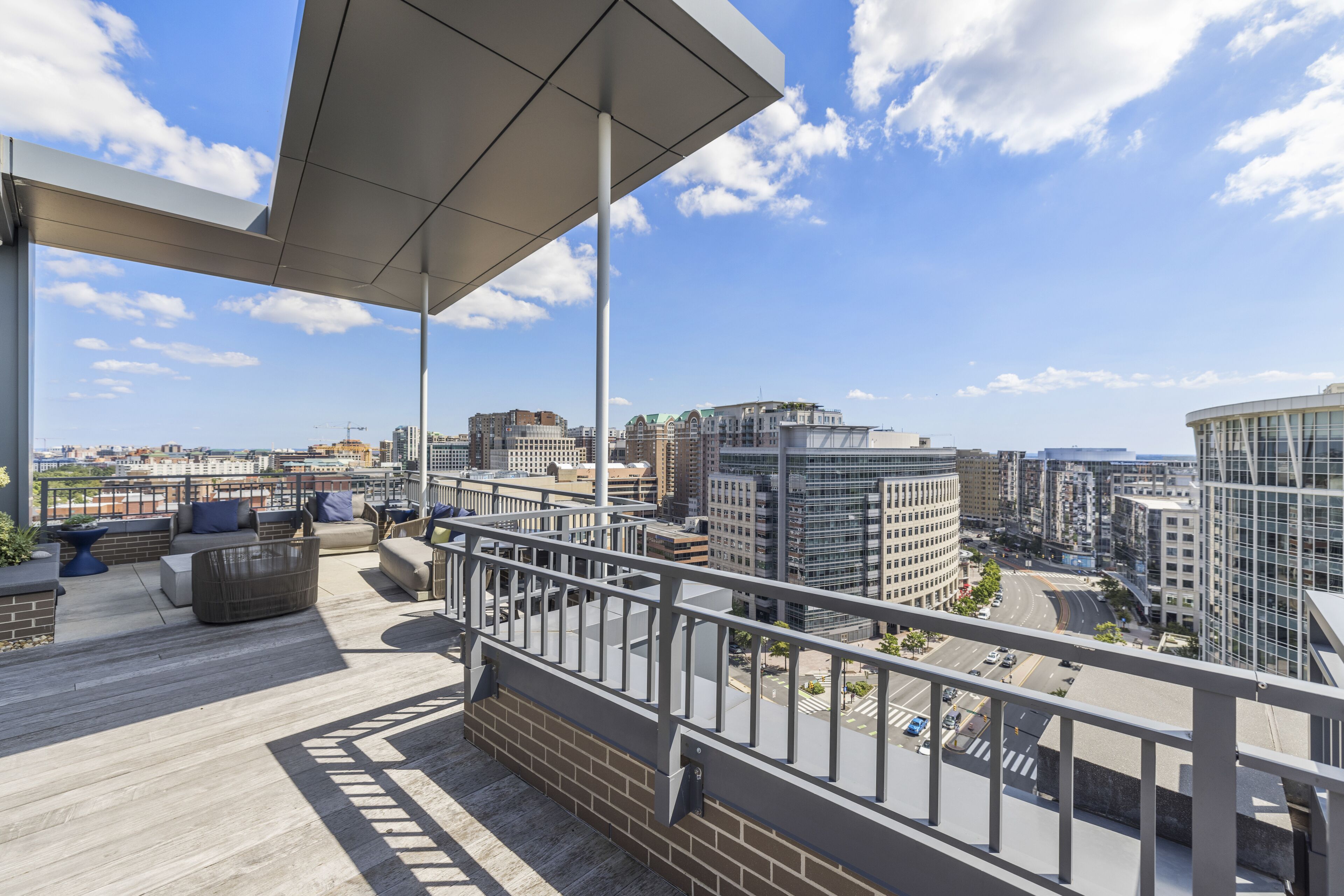 A rooftop terrace with a view of the cityscape, including modern buildings and a clear sky.