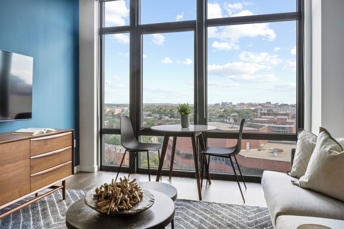 A modern living room with a large window, a round table, and a sofa.
