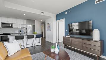 A modern living room with a sofa, coffee table, and a TV on a stand.