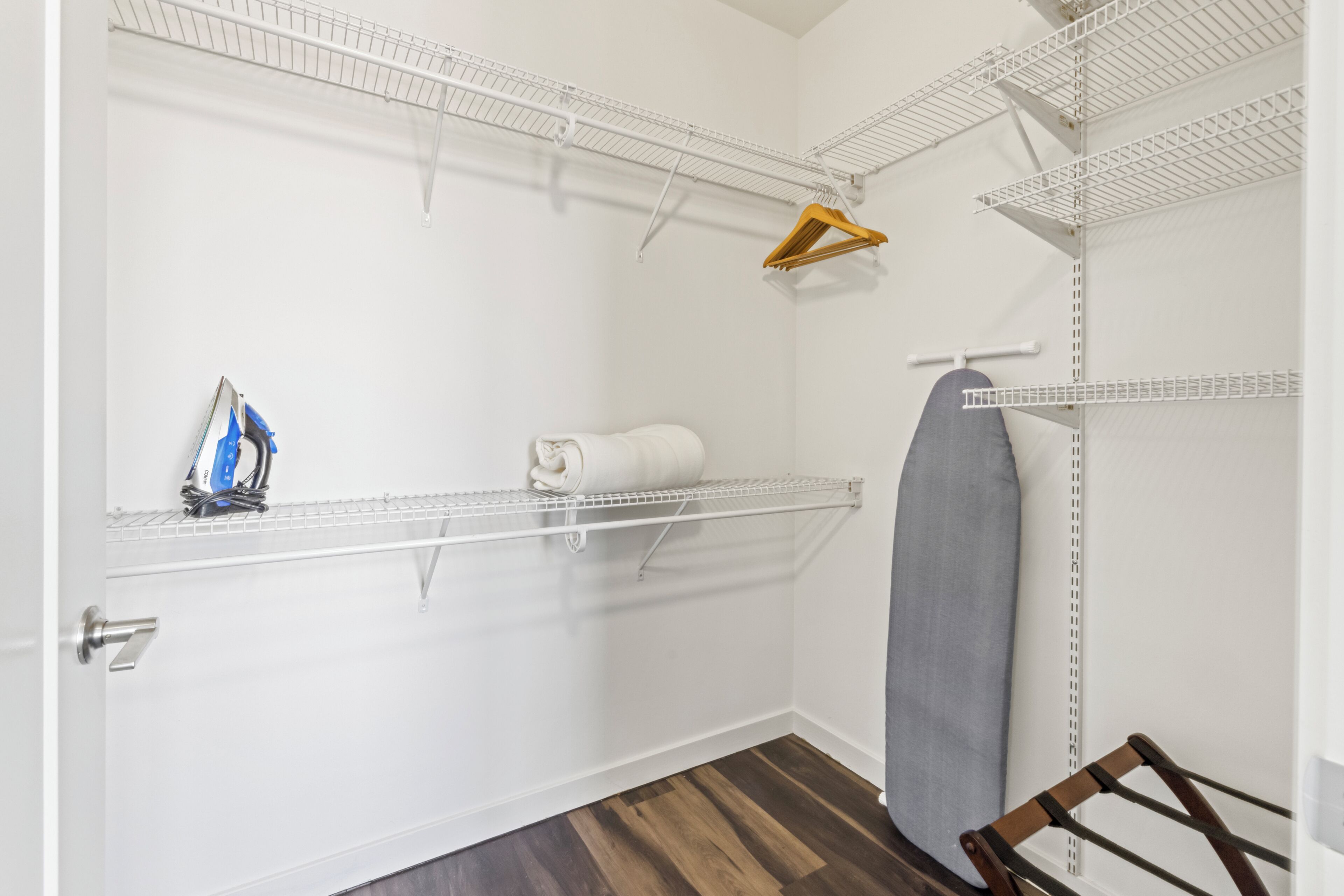 A laundry room with metal shelving units, a drying rack, and a door with a handle.