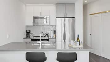 A modern kitchen with white cabinetry, stainless steel appliances, and a central island with two bar stools.