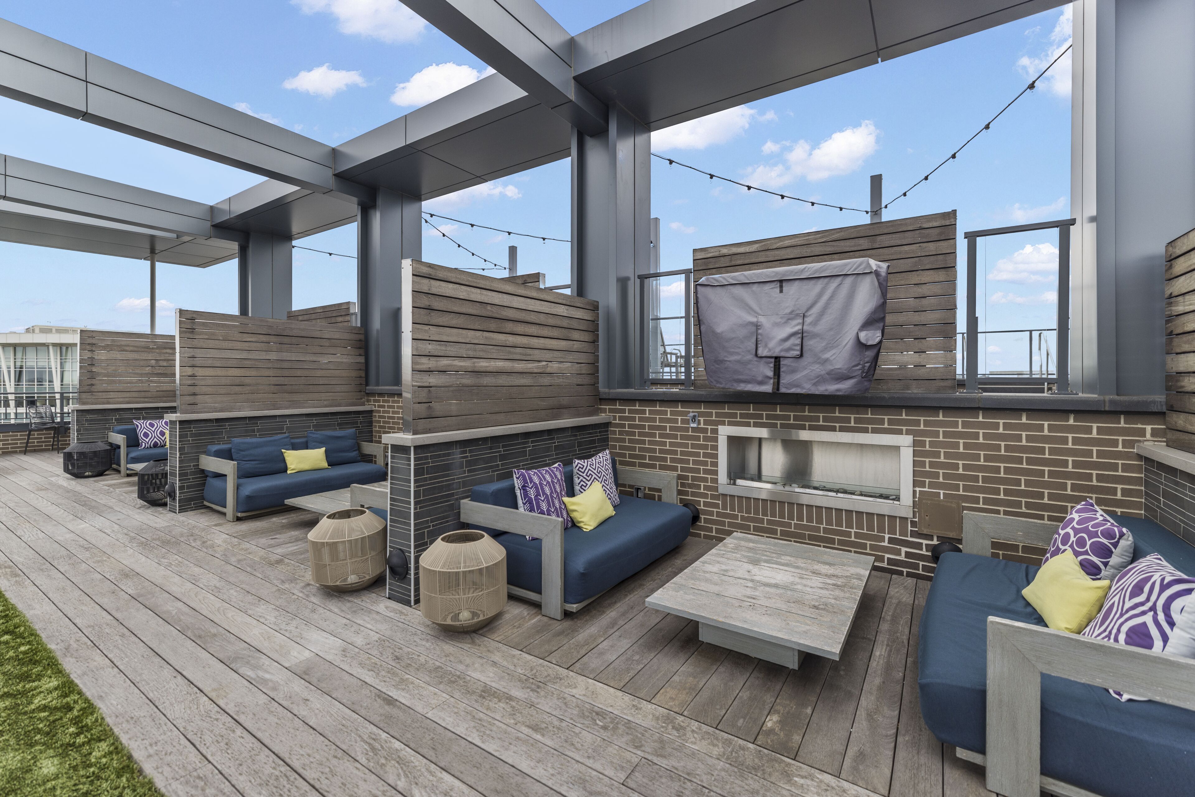 An outdoor patio area with multiple seating options, including sofas and a table, and a brick wall with a window.