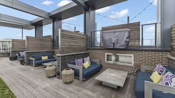 An outdoor patio area with multiple seating options, including sofas and a table, and a brick wall with a window.