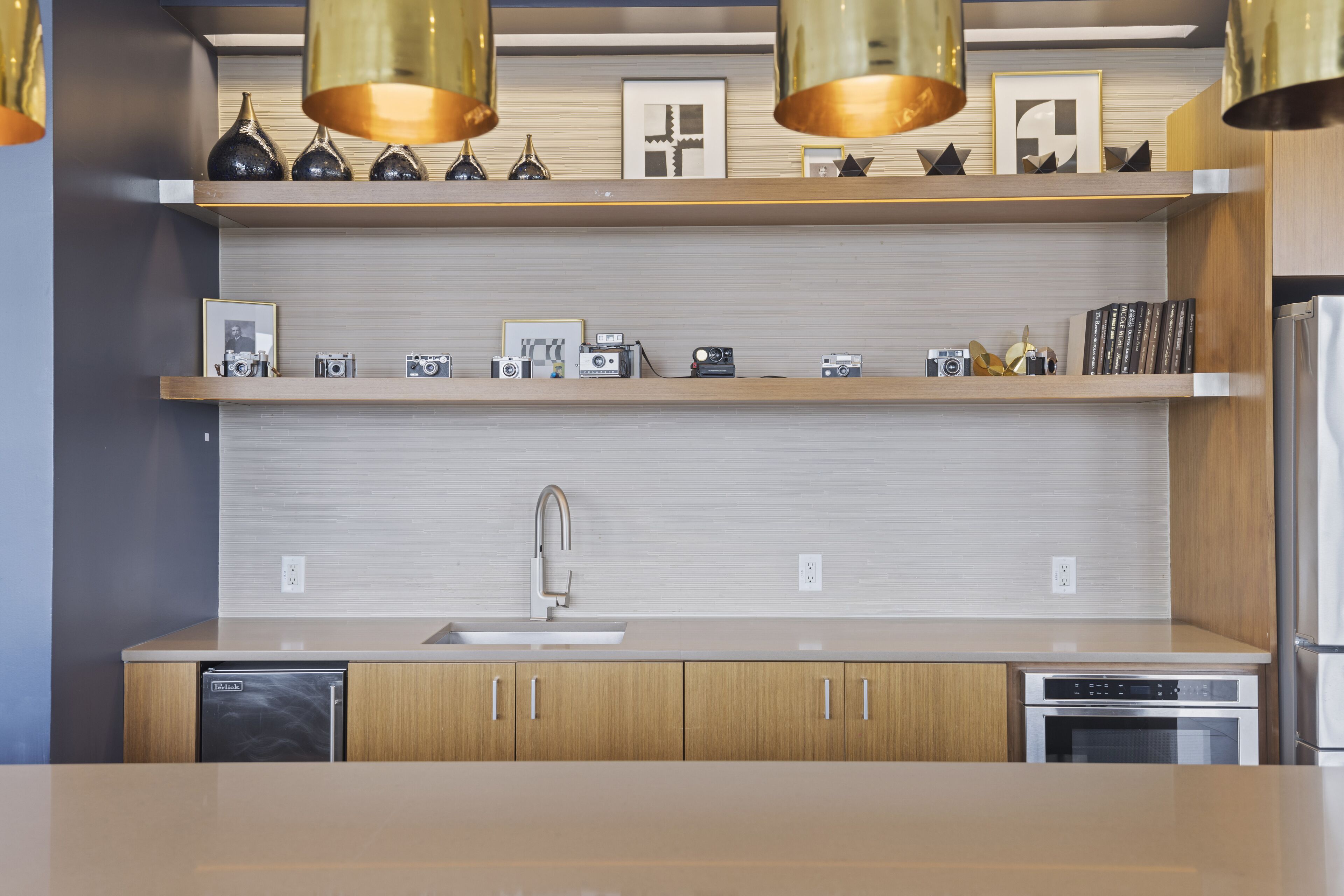 A modern kitchen with wooden cabinets, a stainless steel sink, and a built-in oven.