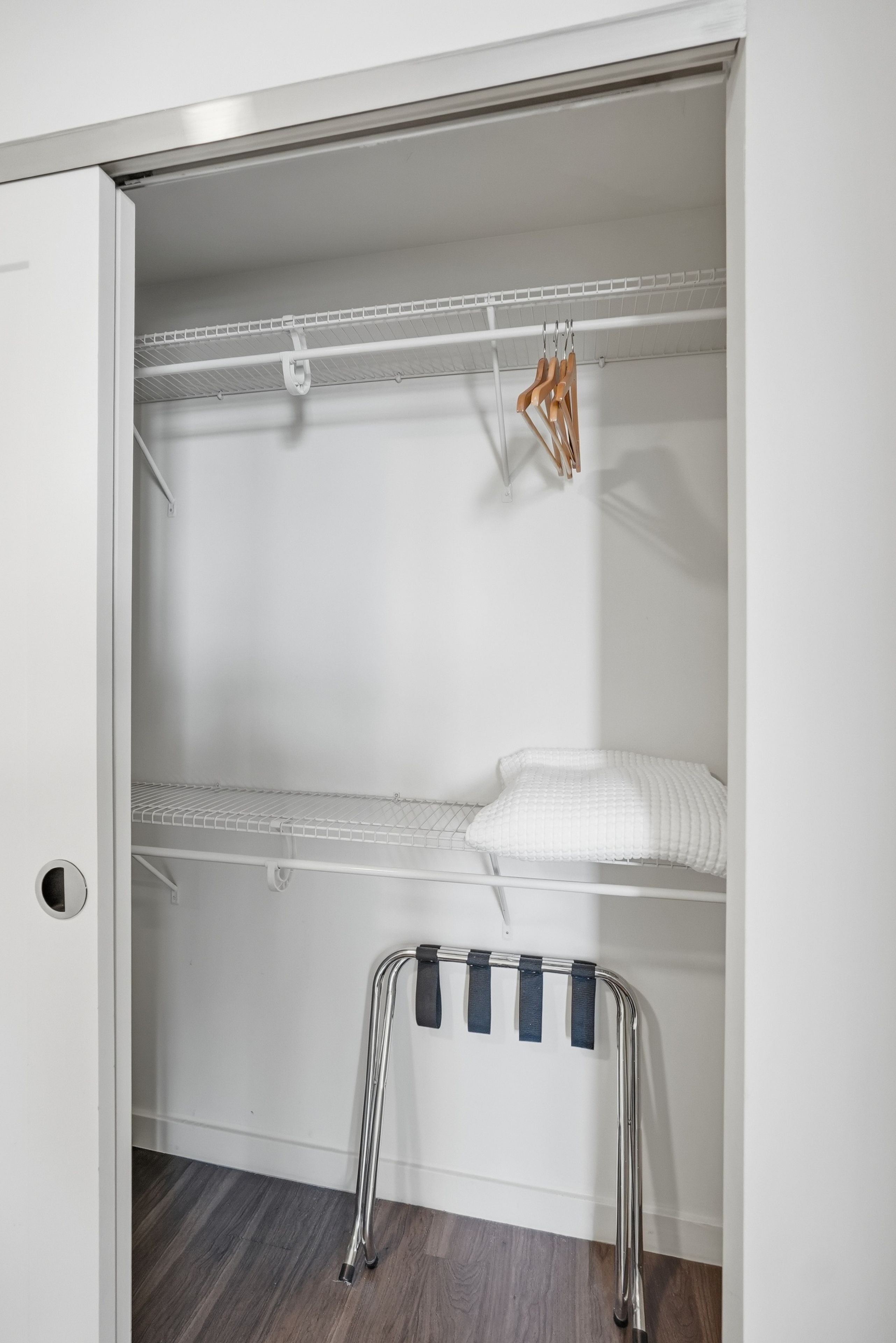 A walk-in closet with a metal bench, shelves, and hanging space.