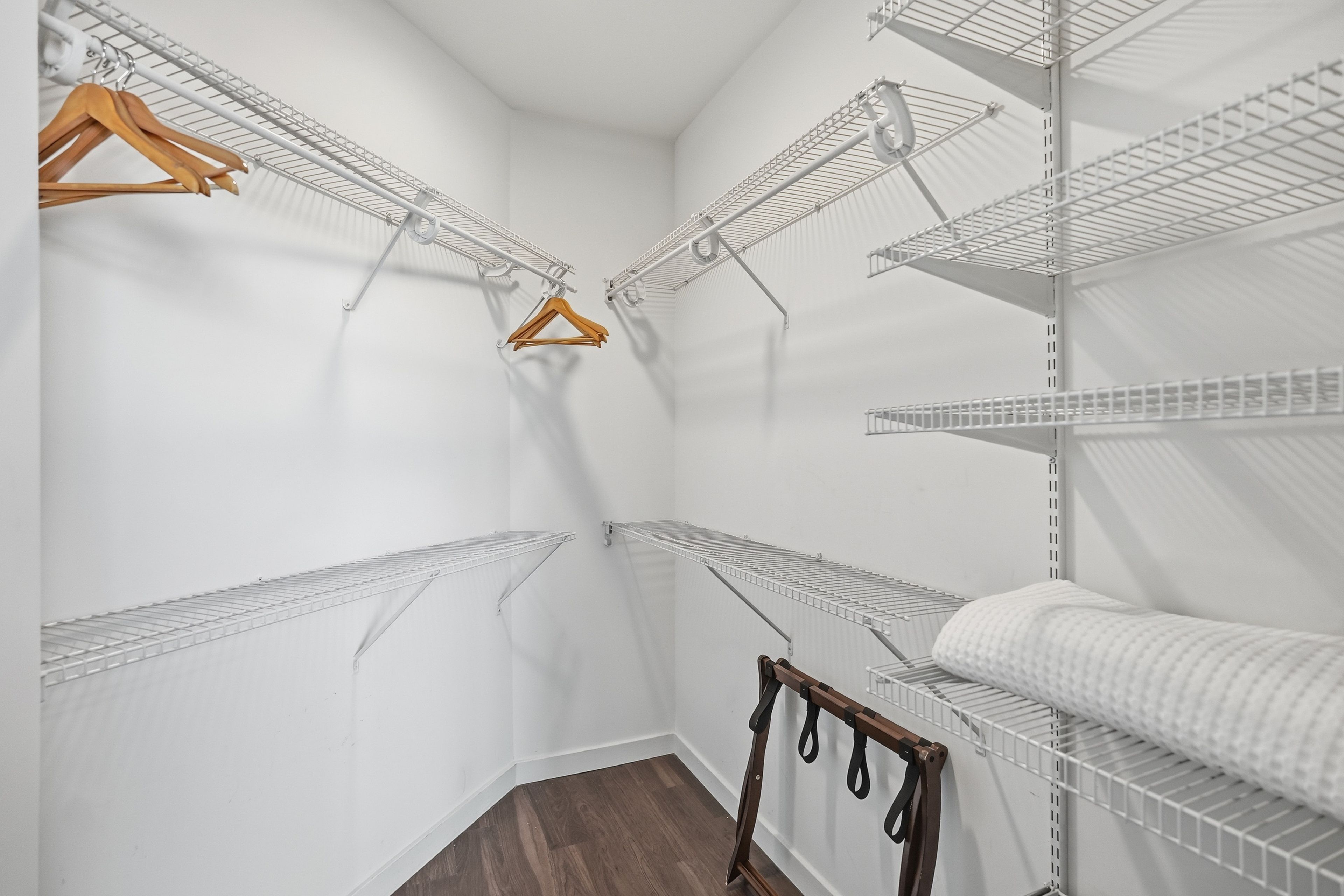Un closet amplio con varias estanterías metálicas y perchas de madera.