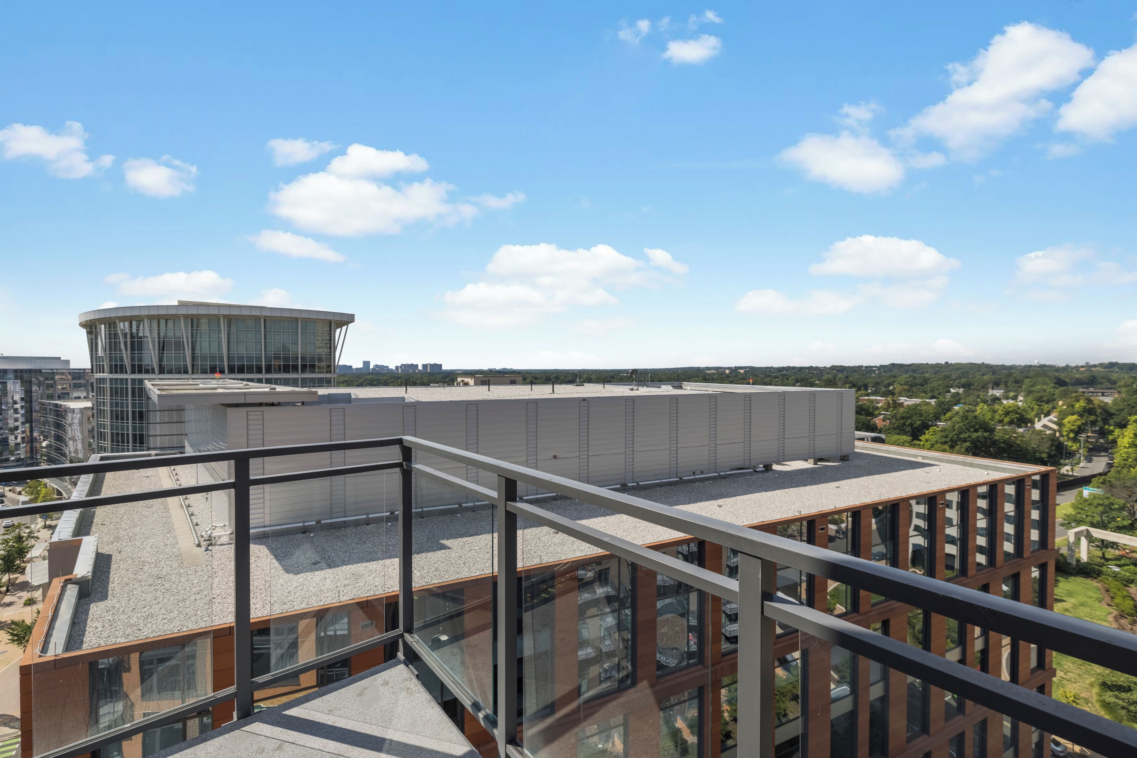 A modern building with a glass facade and a rooftop terrace.