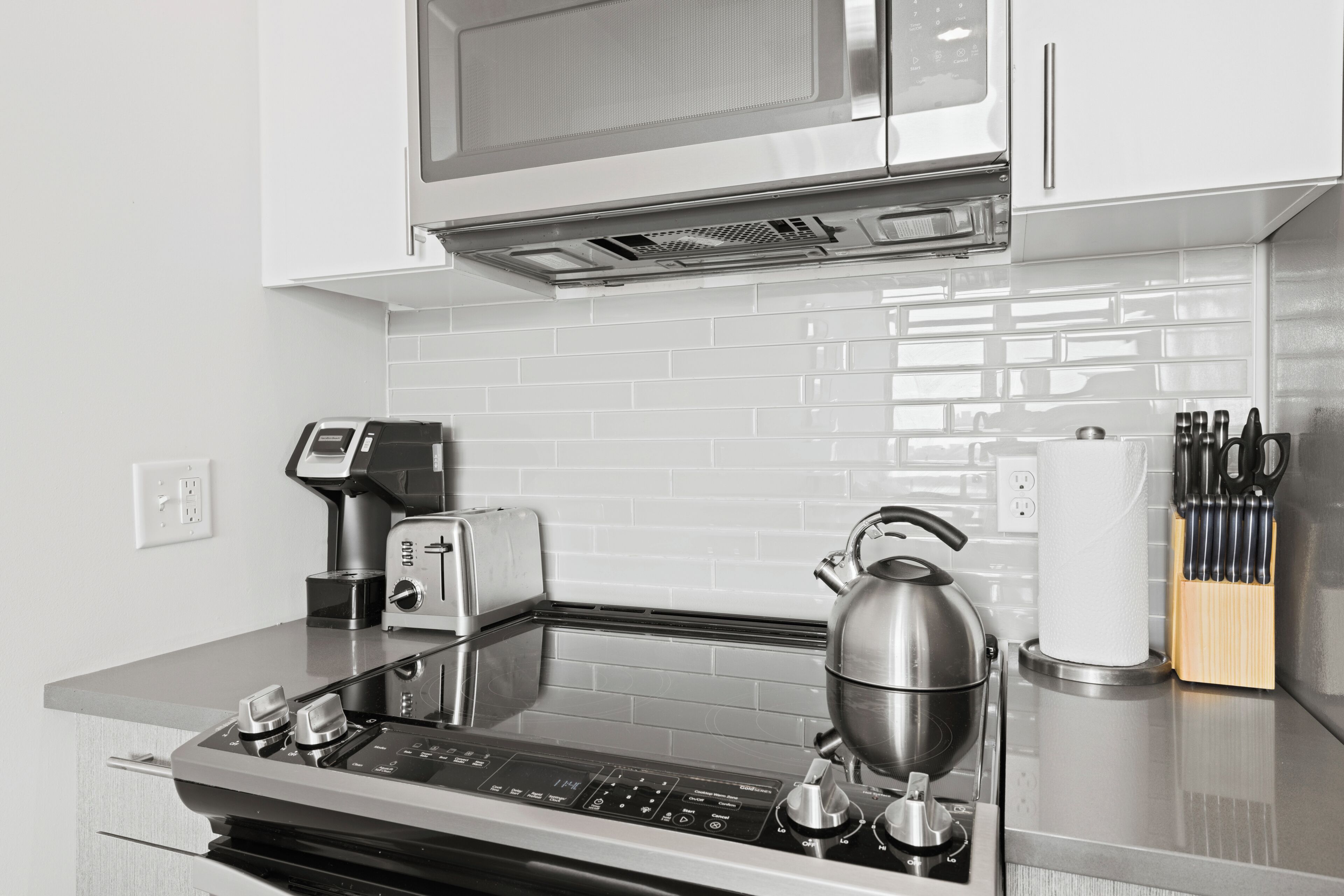 Una cocina moderna equipada con microondas, tostadora, hervidor y cafetera.