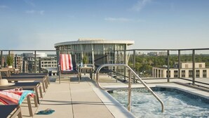 A rooftop pool area with lounge chairs, a hot tub, and a view of the cityscape. - Placemakr Marymount Ballston (Arlington)