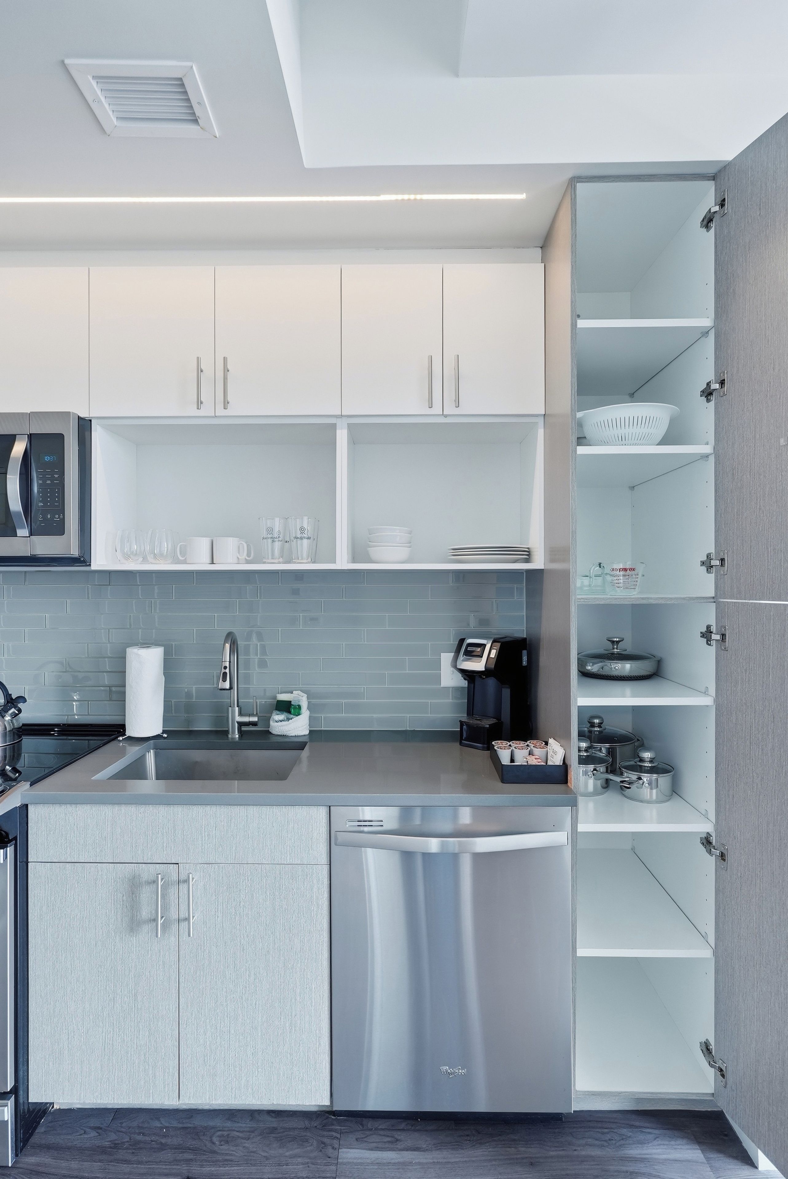 Une cuisine moderne dotée d’appareils électroménagers en acier inoxydable, de meubles blancs et d’un lave-vaisselle encastré.