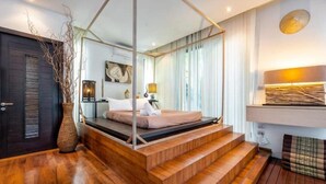 Un dormitorio moderno con piso de madera, una cama con dosel, un espejo grande y una mesita de noche con lámpara.