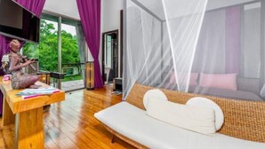 Una habitación moderna con piso de madera, un sofá blanco y un ventanal con mosquitero.