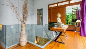 Un interior moderno con un jarrón grande, una estatua y vistas al verde exterior.