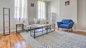 Una sala de estar con un sofá gris, un sillón azul, una mesa de centro y un tapete estampado.