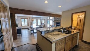 Un'ampia cucina con un'isola grande, mobili in legno e una schiena di pietra.