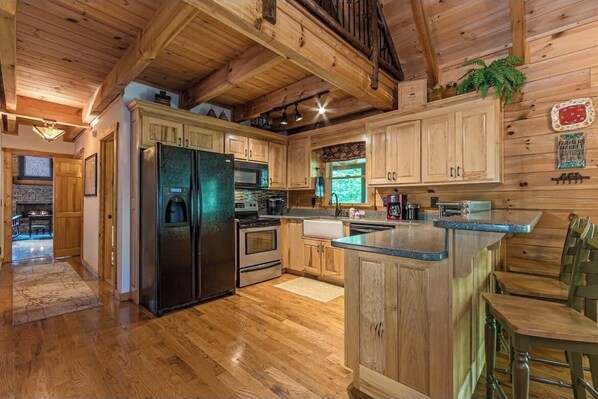 Enjoy cooking in this well-equipped kitchen with a central island, refrigerator, stove, and microwave.