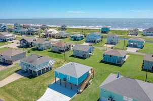 A coastal residential area with houses featuring a mix of single and two-story structures, some with attached garages and others with separate buildings.