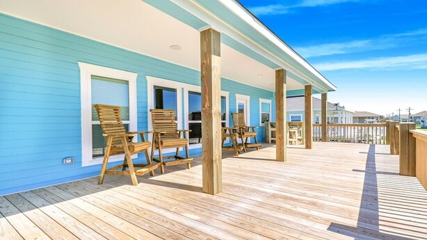 Eine Holzterrasse mit Stühlen und einem überdachten Bereich, vermutlich eine Terrasse oder ein Deck.