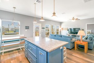 A modern kitchen with granite countertops, blue cabinets, and pendant lighting.