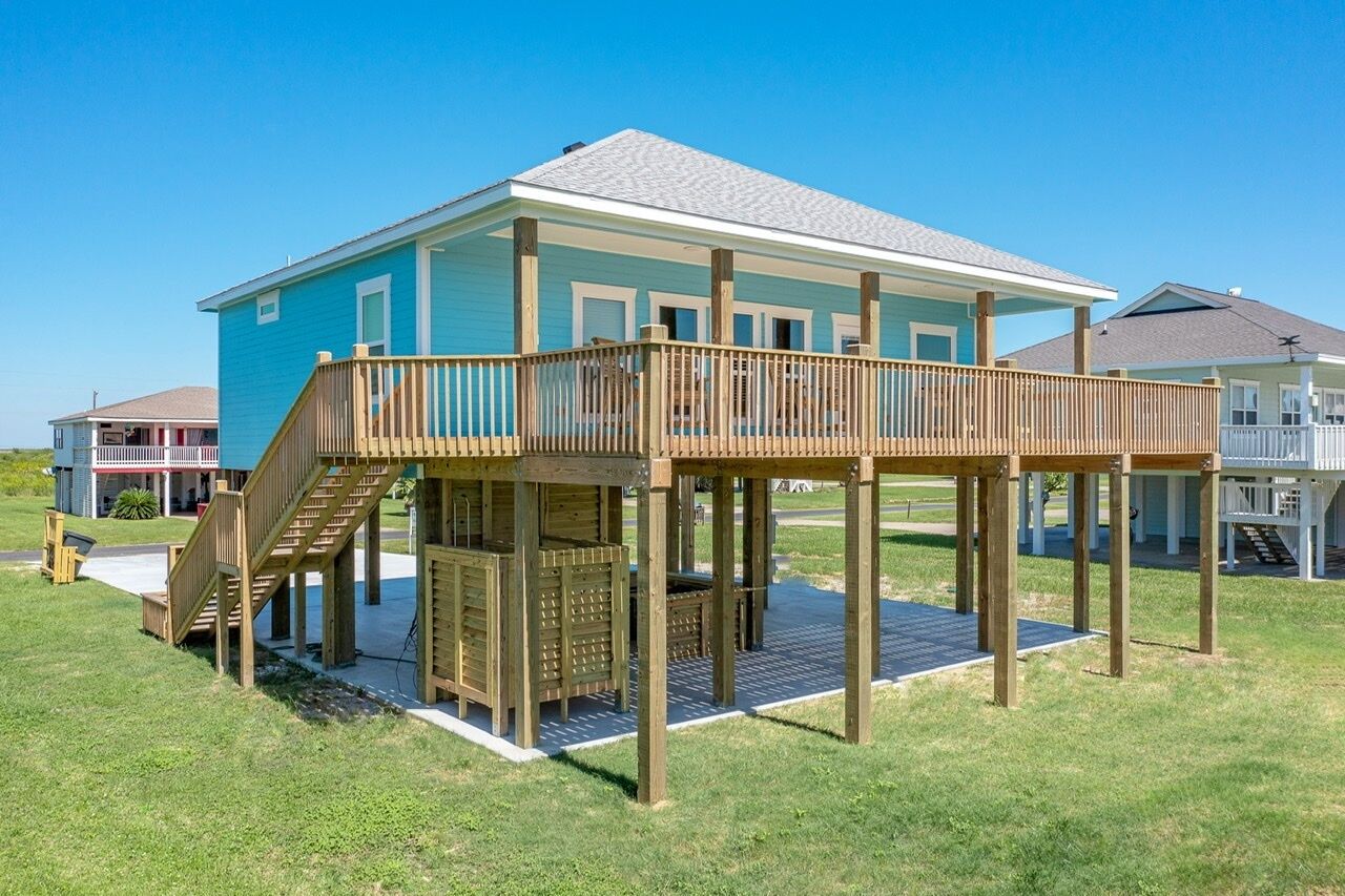 A two-story house with a wooden deck and a staircase leading to the upper level.
