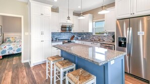 Eine moderne Küche mit weißen Schränken, einem Edelstahl-Kühlschrank und einer blauen Kochinsel mit Barhocker.