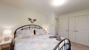 Een slaapkamer met een bed, twee bedlampen, een wanddecoratie en een stel witte deuren.