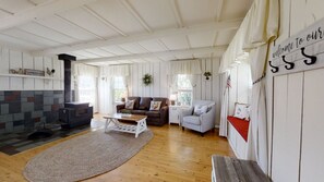 Een ruime woonkamer met een open haard, een bank, een salontafel en een vloerkleed.