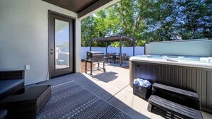 An outdoor patio with a grill, hot tub, and seating area.