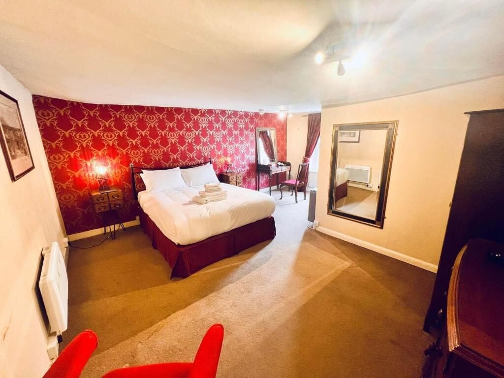 Habitación de hotel con una cama grande, un escritorio, una silla y un espejo.