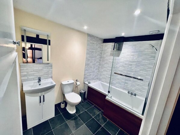 Un baño moderno con lavamanos, inodoro y bañera blancos.