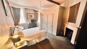 A bedroom with a bed, bedside tables, a dresser, a mirror, and a fireplace. - George and Dragon Hotel (High Wycombe)