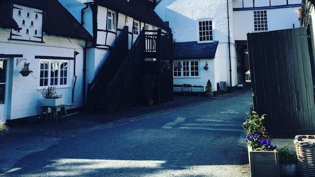 A narrow street with traditional half-timbered houses, a visible staircase, and a clear blue sky. - George and Dragon Hotel (High Wycombe)
